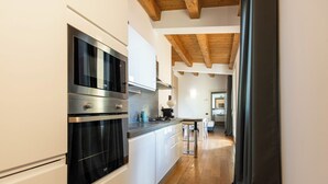 Una cocina moderna con electrodomésticos integrados, techo de madera y vista al área de comedor.