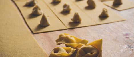 A wooden table with pasta sheets and uncooked pasta shapes.