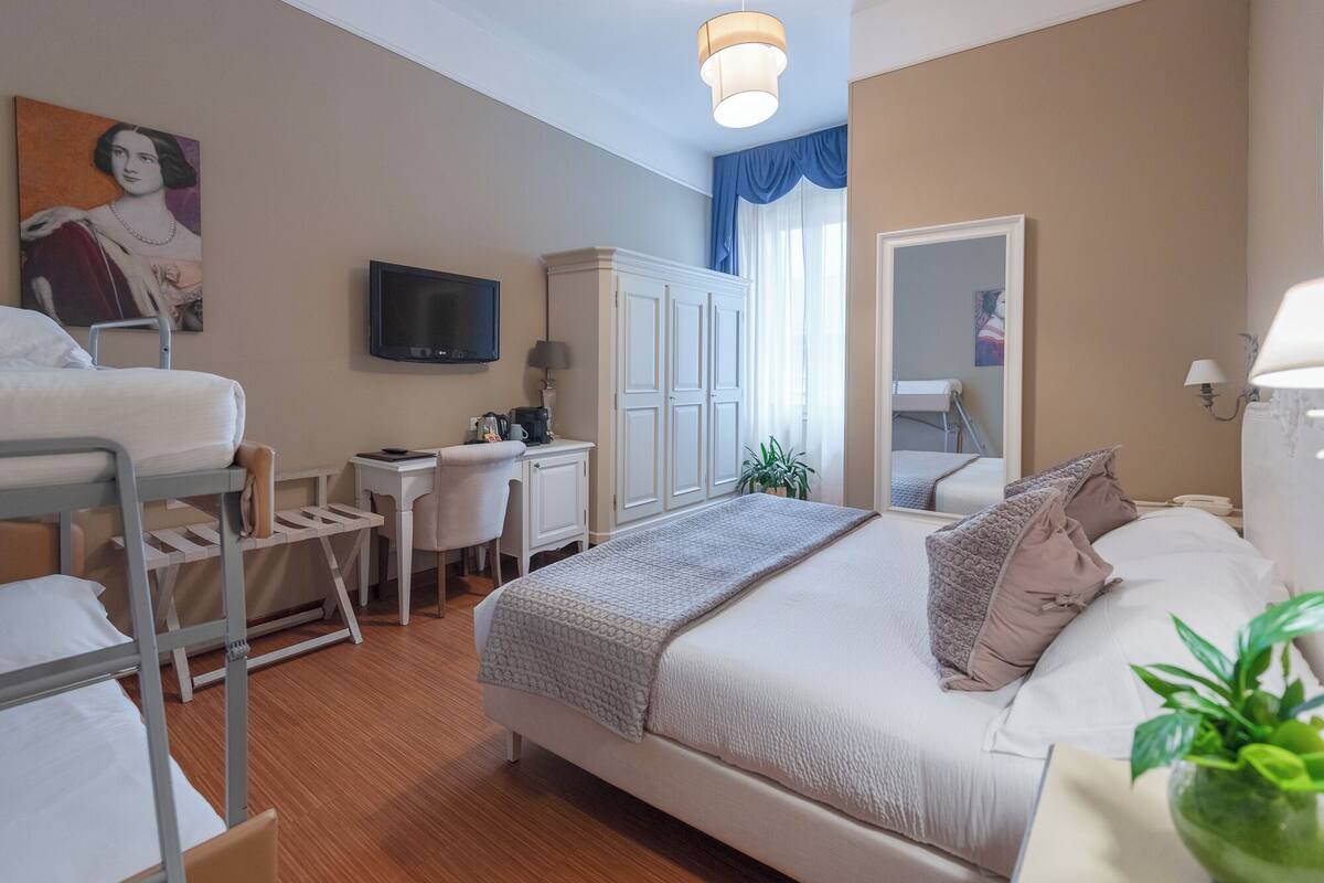 A hotel room with a bed, desk, chair, and a television.