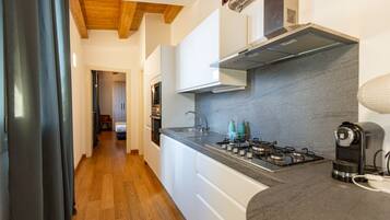 Una cocina moderna con armarios blancos, una estufa a gas y un lavaplatos de acero inoxidable.