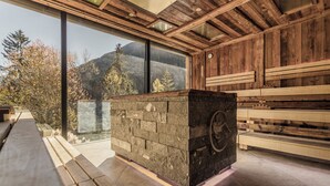 Un interior de madera con chimenea de piedra, ventanas amplias y vistas a montañas.