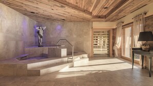 Un área de spa con una bañera de hidromasaje de piedra, techo de madera y vistas al exterior.