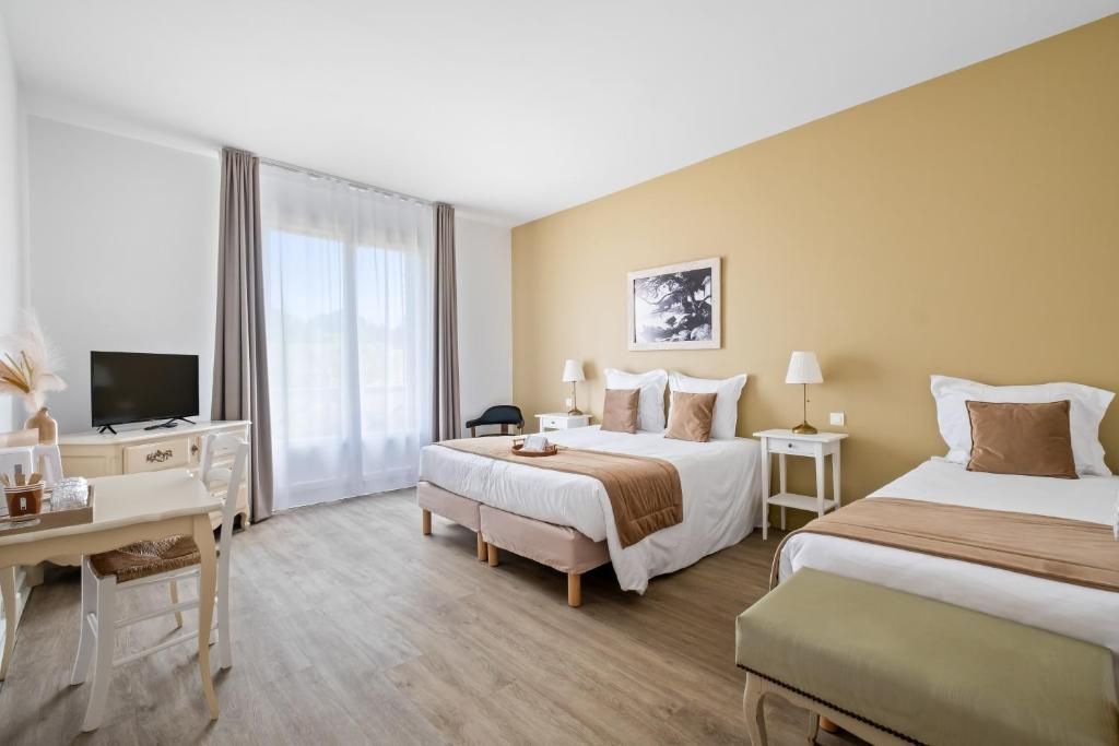 Habitación de hotel con cama, mesitas de noche, escritorio, silla, televisor y ventana con cortinas.