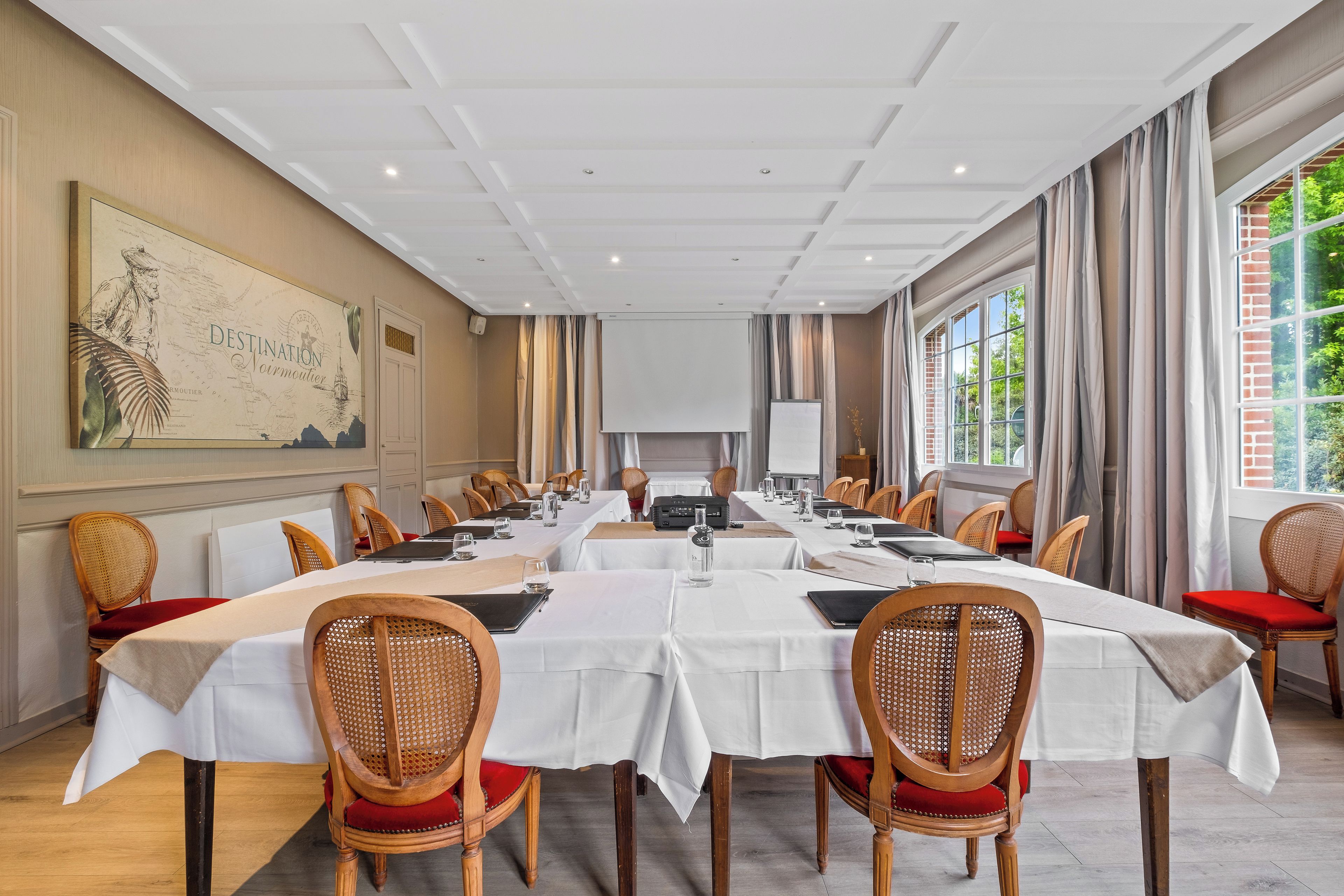 Une salle de conférence avec de longues tables, des chaises en osier et une grande carte accrochée au mur.