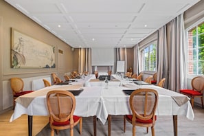 A conference room with long tables, wicker chairs, and a large map on the wall.