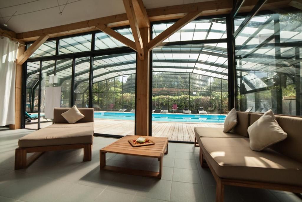 A modern indoor pool area with wooden furniture and glass walls.