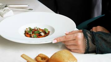 A person serving food from a copper pot to a white plate.