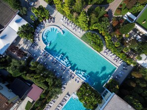 An aerial view of a resort with a large swimming pool, sun loungers, and lush greenery. - ABANO GRAND HOTEL – Lifestyle Spa & Fine Dining (Abano Terme)