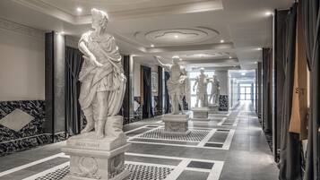 Un pasillo con suelo de mármol, estatuas clásicas y un diseño interior moderno.