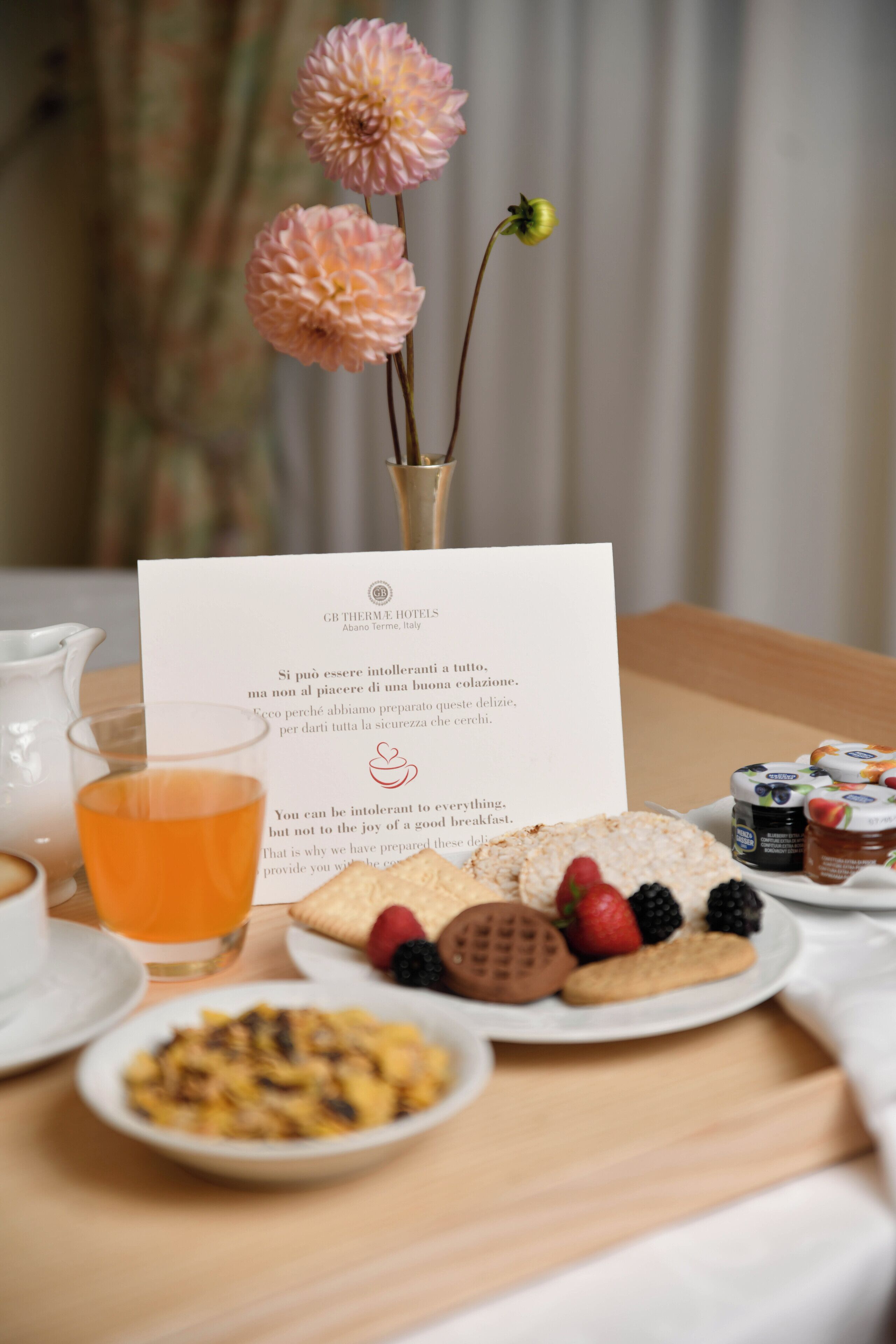 Une table mise pour le petit-déjeuner, avec un menu, un vase rempli de fleurs et divers aliments destinés au petit-déjeuner.