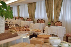 A dining area with multiple tables set for breakfast, featuring an assortment of pastries and bread. - ABANO GRAND HOTEL – Lifestyle Spa & Fine Dining (Abano Terme)