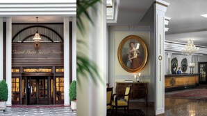 Une grande entrée d'hôtel avec une porte tournante, un comptoir d'accueil et un lustre.