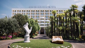 L’extérieur de l’hôtel ABANO GRAND HOTEL présente une pelouse circulaire centrale où figure le nom de l’hôtel.