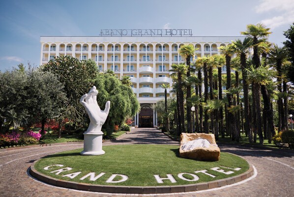 El exterior del ABANO GRAND HOTEL, con un césped circular central que presenta el nombre del hotel.