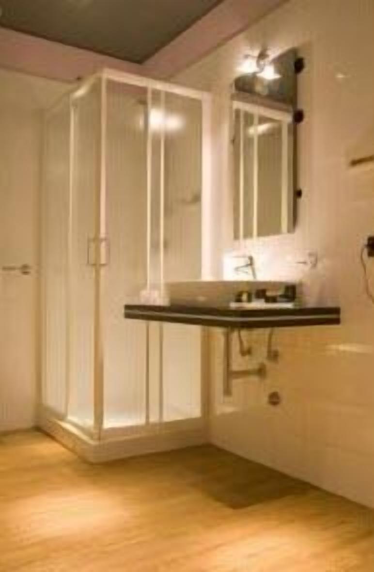 Un baño con cabina de ducha, un lavabo con espejo y un perchero para toallas.