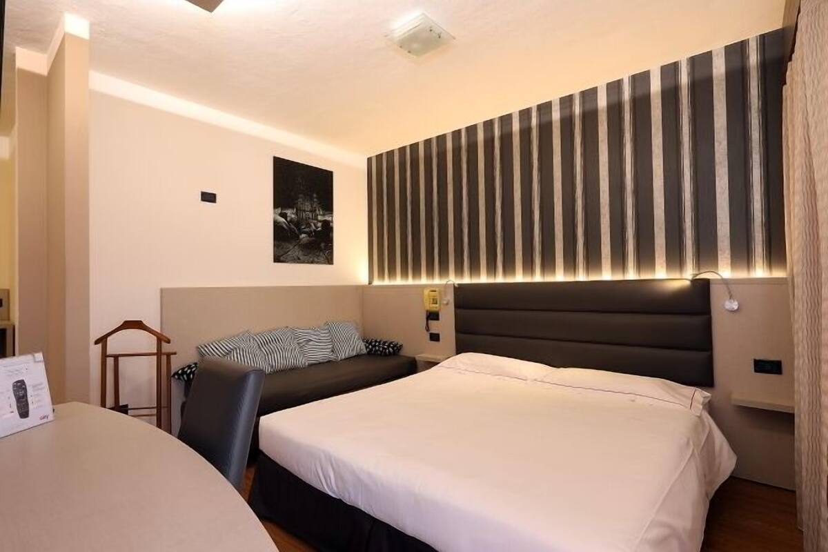 Habitación de hotel con dos camas, un escritorio y un cabecero a rayas.