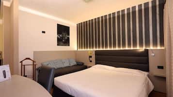 Habitación de hotel con dos camas, un escritorio y un cabecero a rayas.
