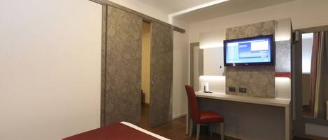 A hotel room with a bed, a desk with a chair, a TV, and a sliding door.