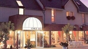 A boutique hotel with a classic European architectural style, featuring a prominent arched entrance and a well-lit facade. - LOGIS Chez Bach (Chaussin)