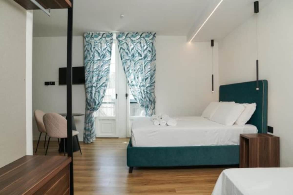 Un dormitorio moderno con una cama color turquesa, un escritorio de madera y una silla.