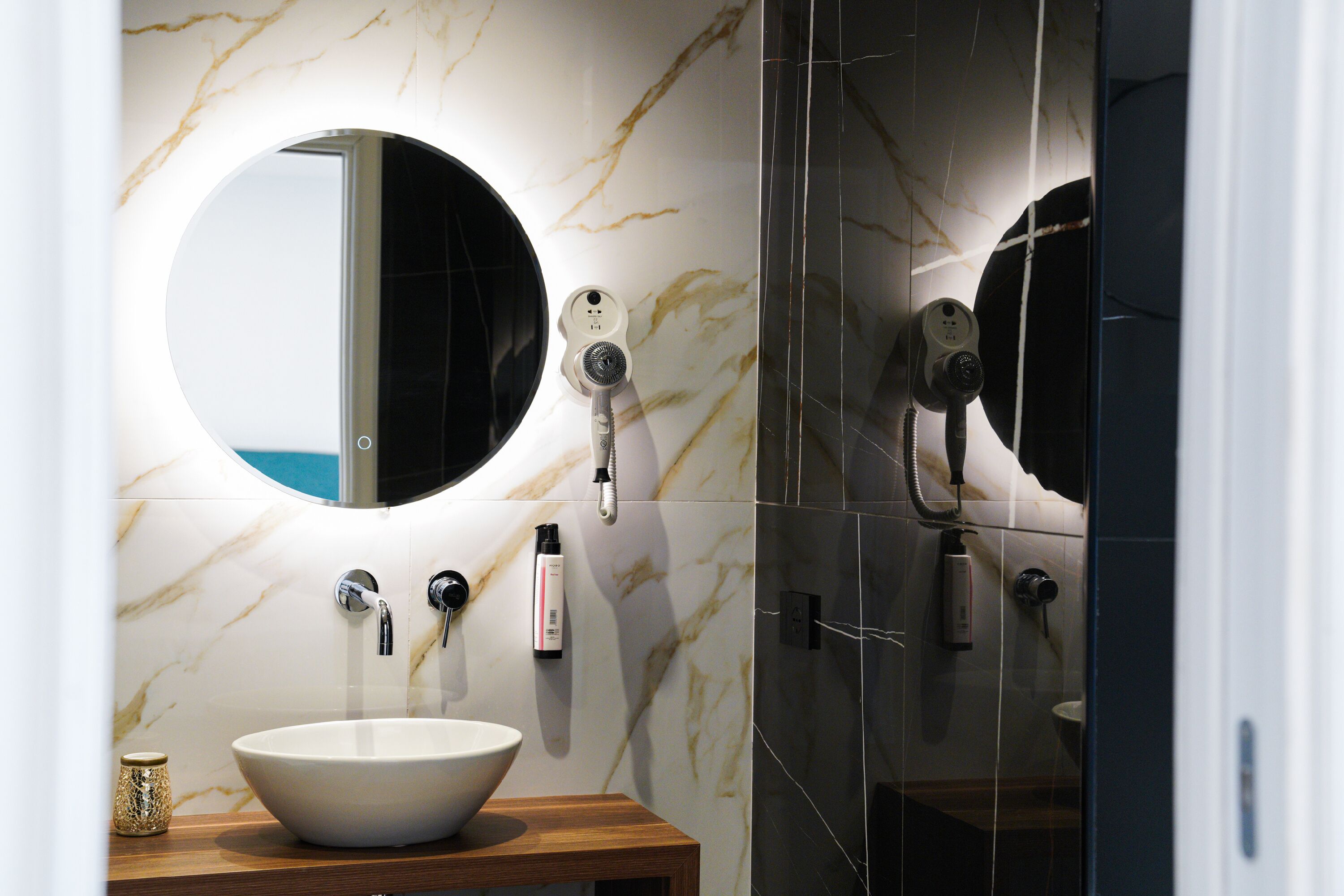 A bathroom with a round mirror, a white sink, and a handheld showerhead.