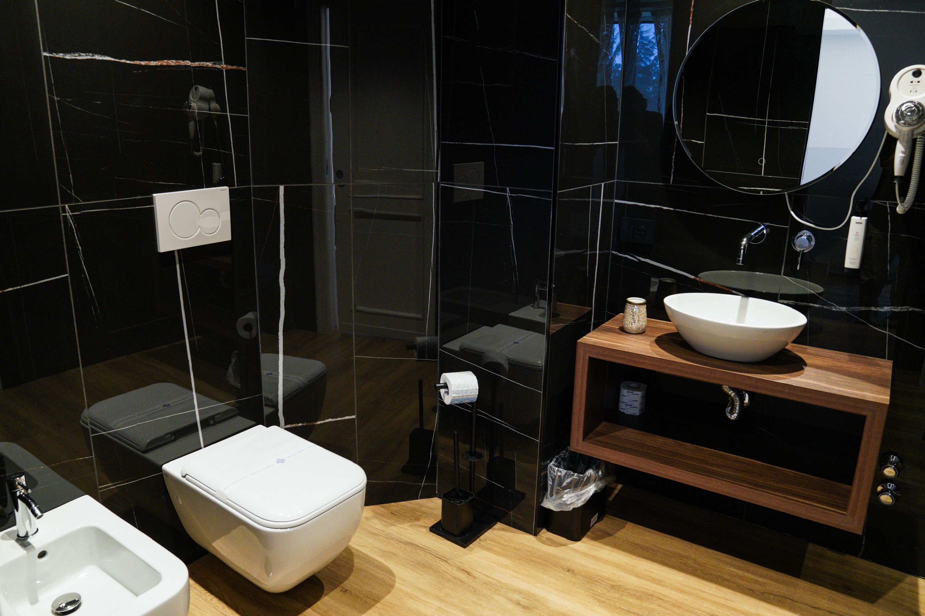 Un baño moderno con inodoro blanco, lavabo y espejo.