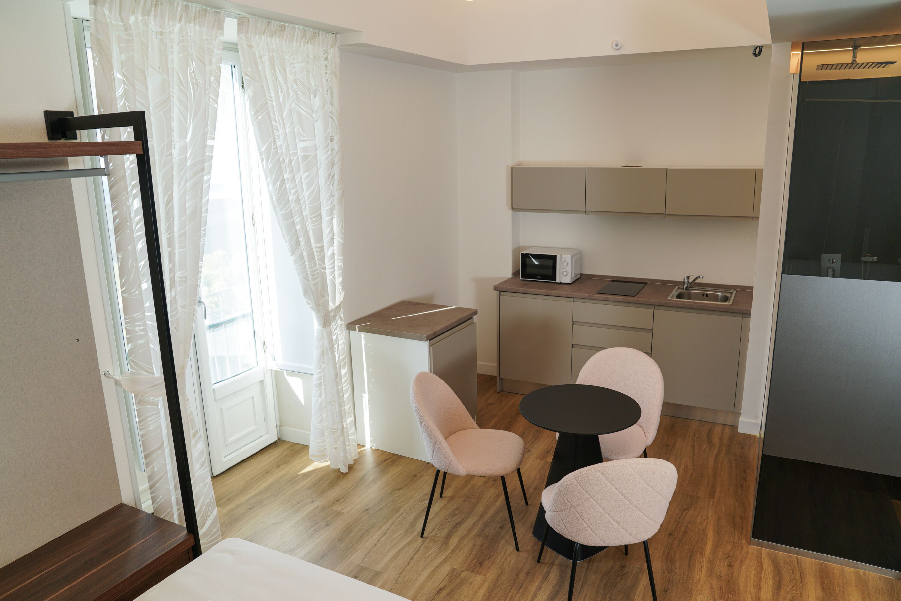 A compact kitchen with a microwave, sink, and two chairs.