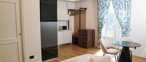 Una habitación de hotel moderna con cama, una mesita, dos sillas, un área de cocina y un baño.