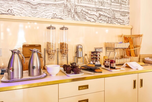 A breakfast buffet with coffee makers, pastries, and condiments.