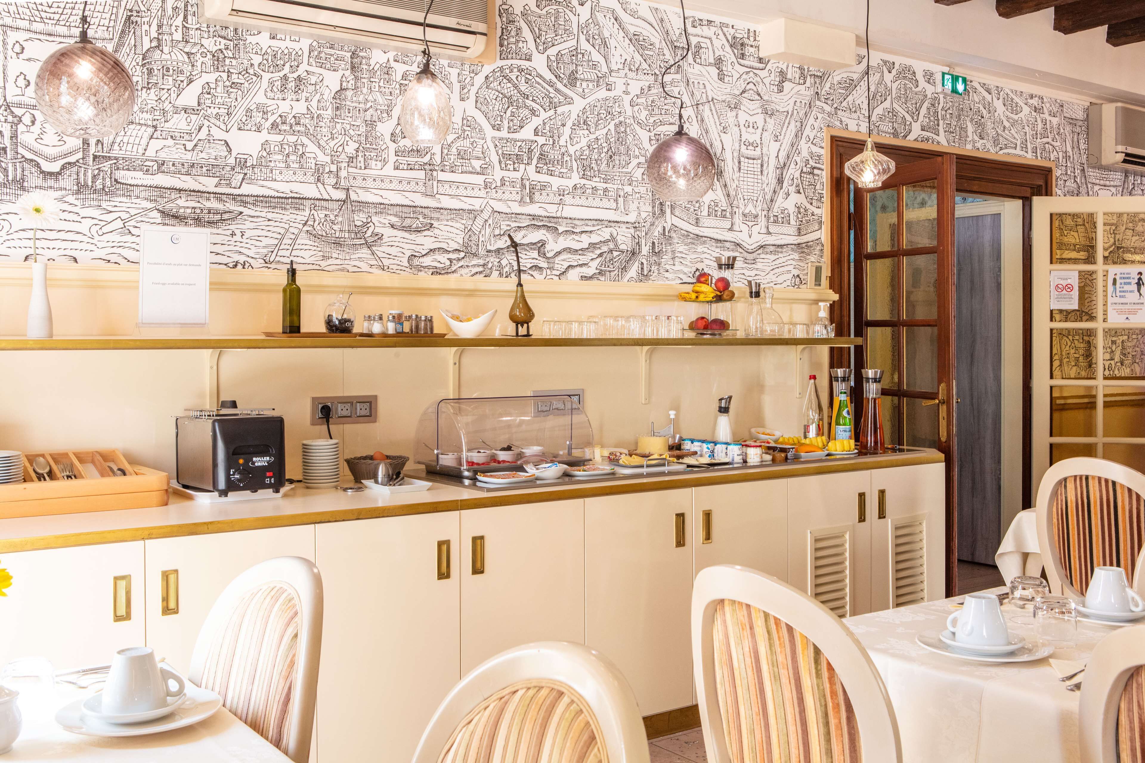 Una barra de desayuno con una pared decorada con motivos de mapa, una máquina de café y una variedad de alimentos para el desayuno.