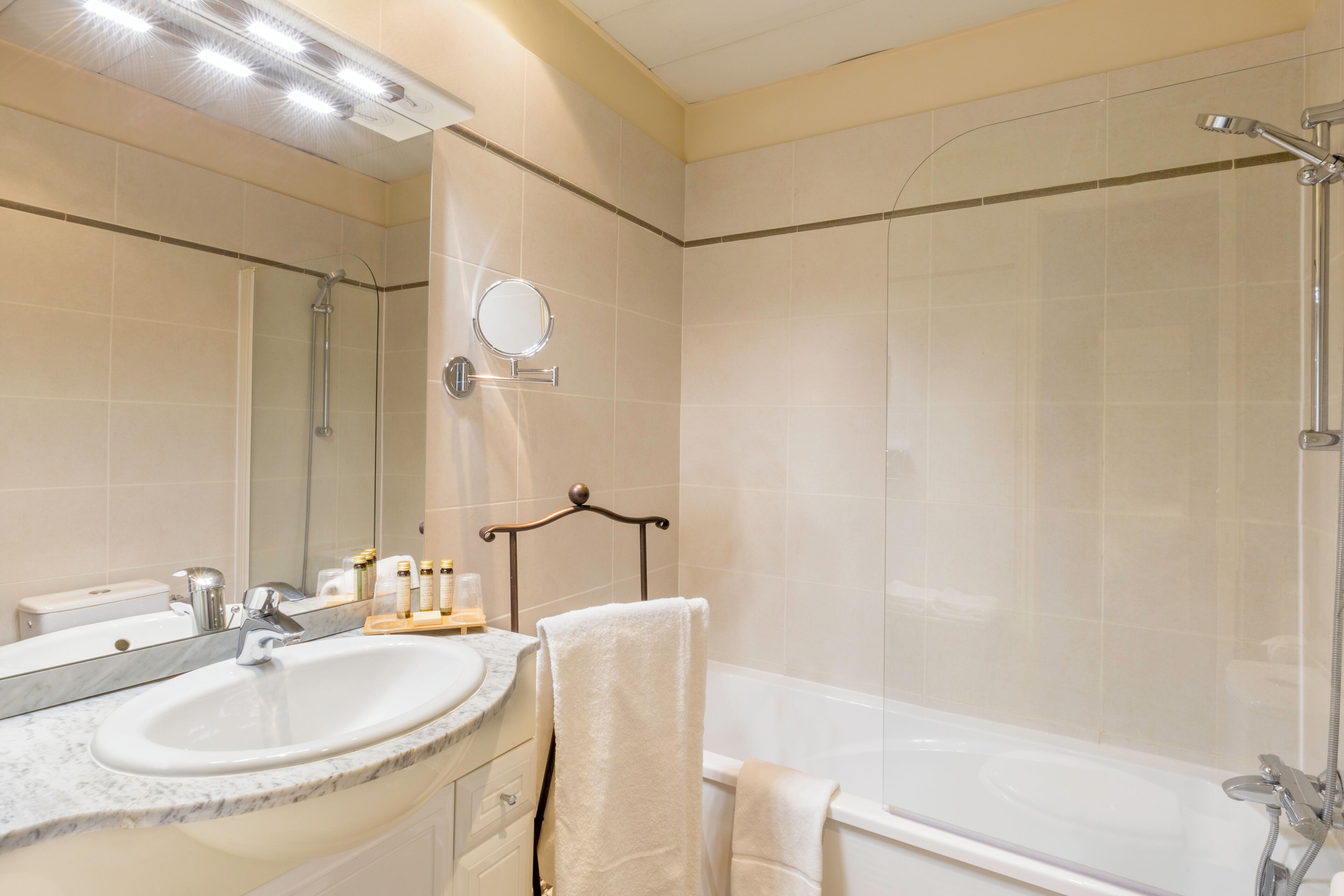 Un bagno con lavabo in marmo, uno specchio, un porta asciugamani e una vasca da bagno.