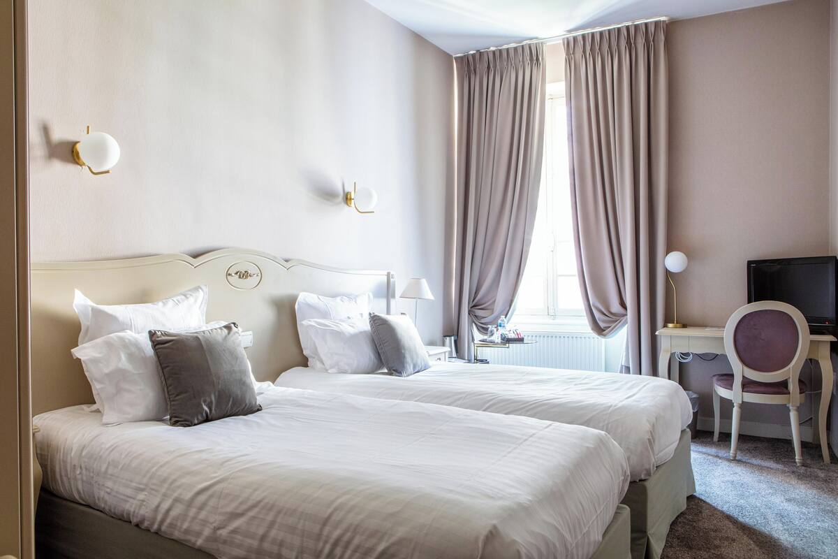 Una habitación de hotel con dos camas, un escritorio, una silla y un televisor.