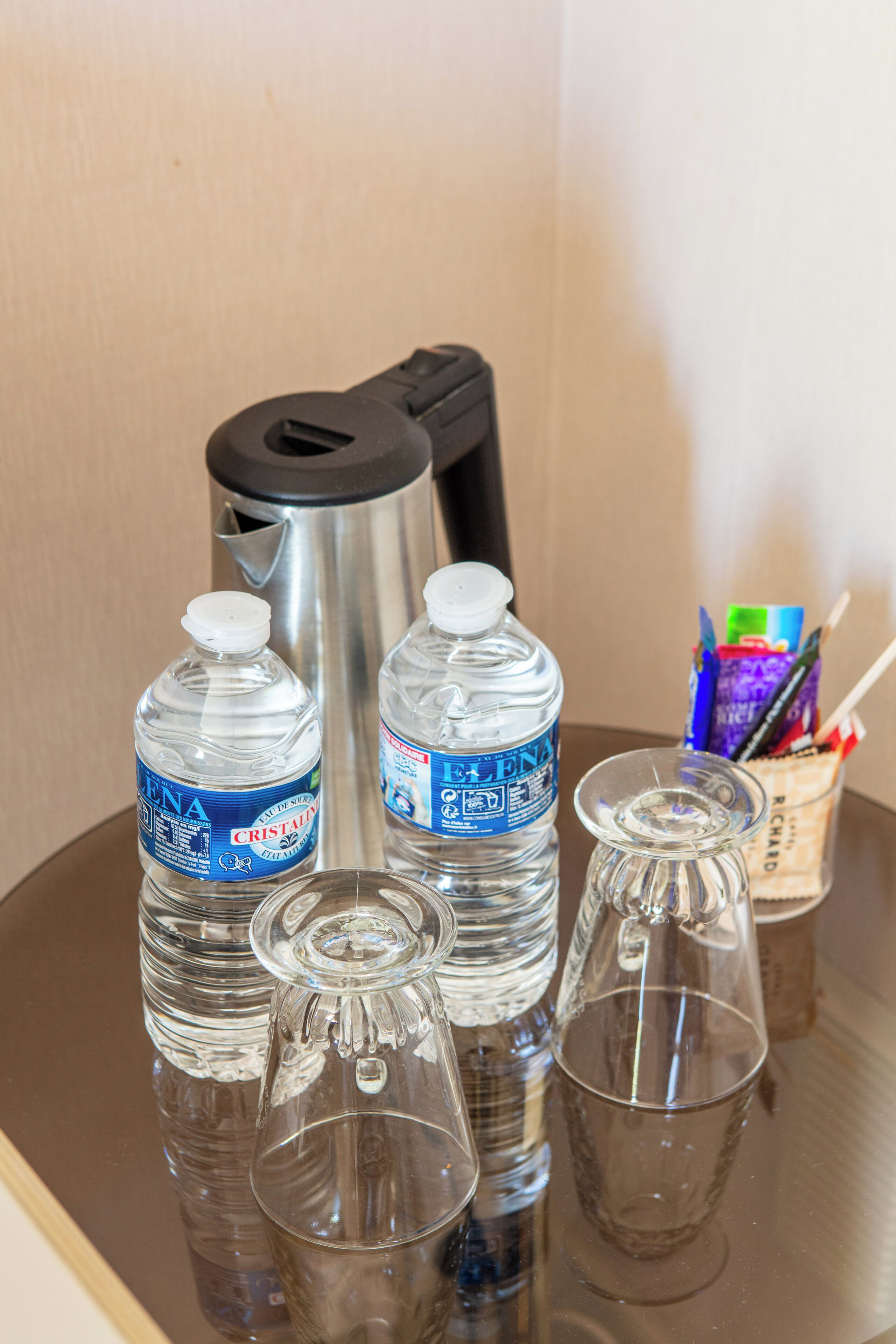 A table with two water bottles, a thermos, and two glasses.
