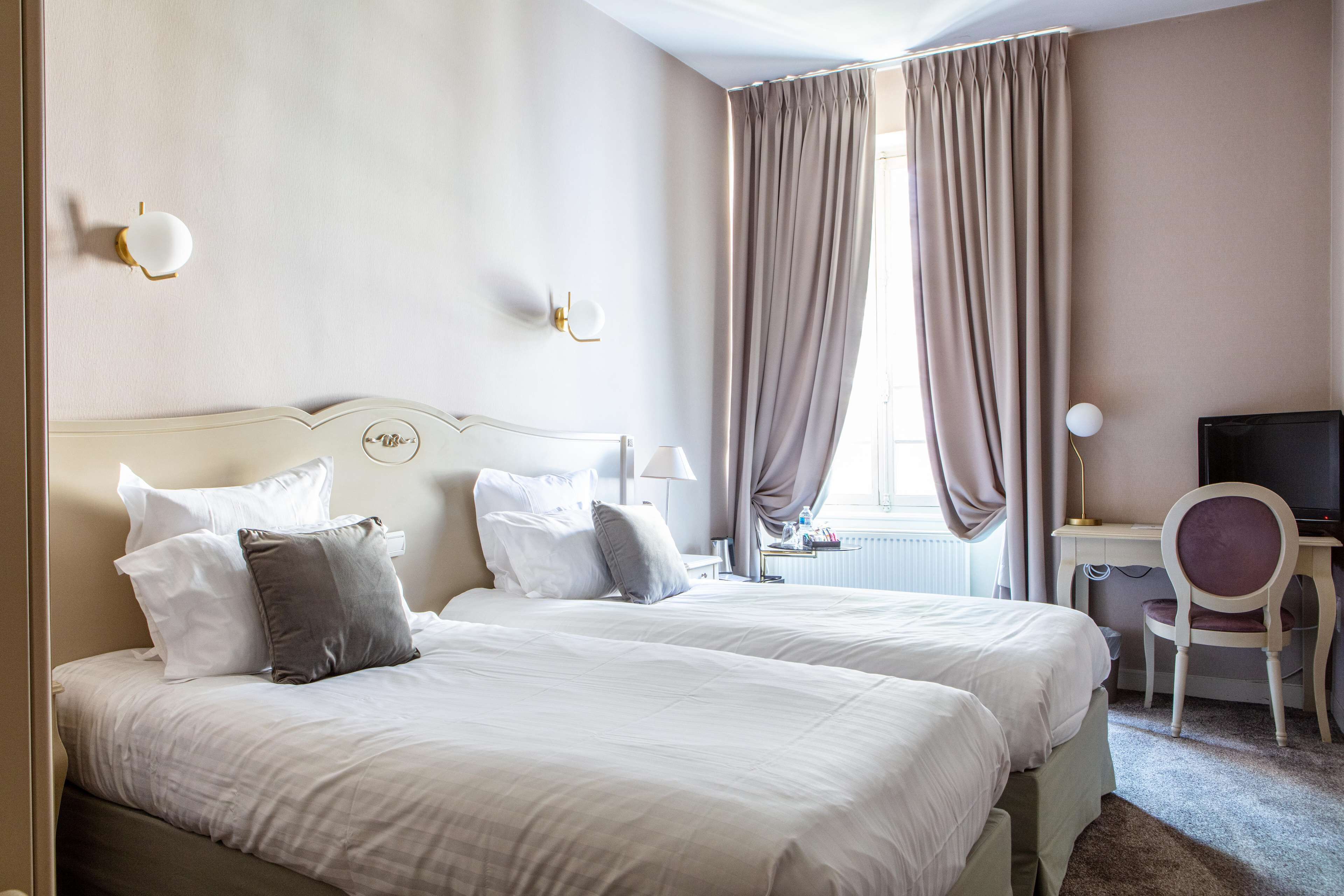 Una habitación de hotel con dos camas, un escritorio, una silla y un televisor.