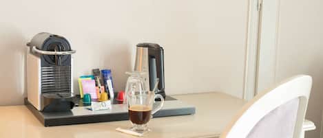 A coffee machine and a glass of coffee on a table.