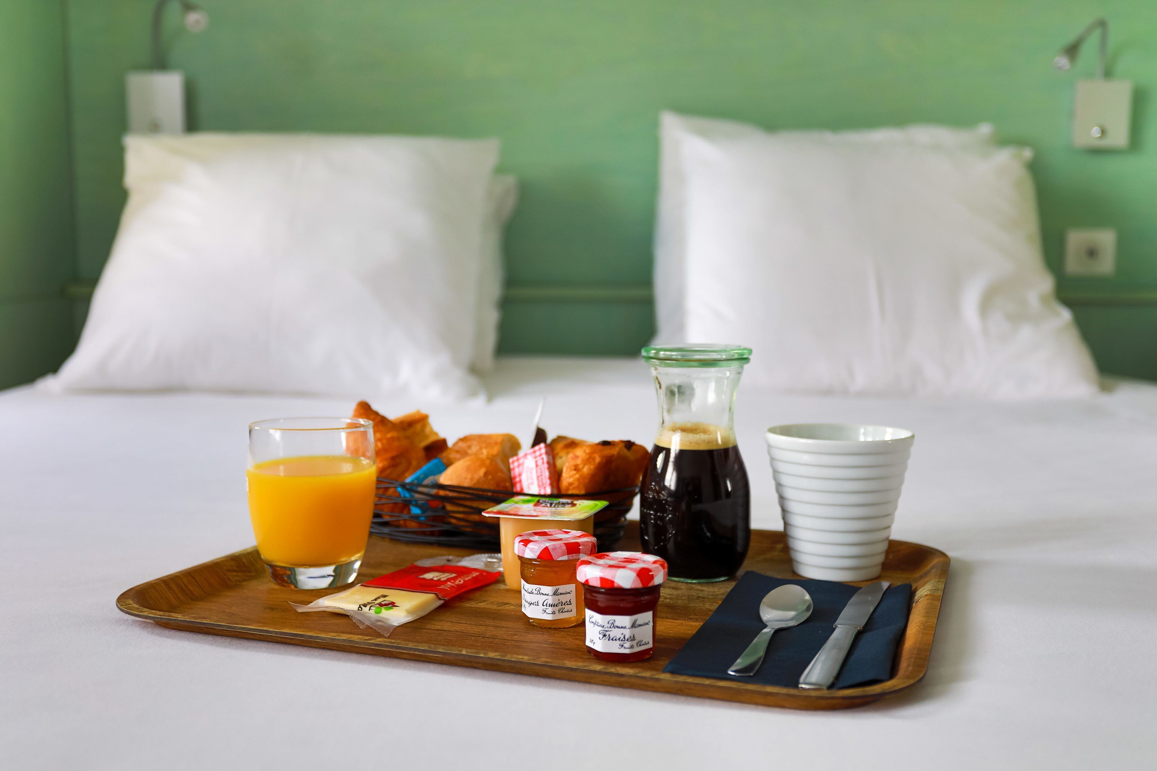 Ein Frühstücksbrett mit Orangensaft, Croissants, Marmelade und einer Kaffeekanne.