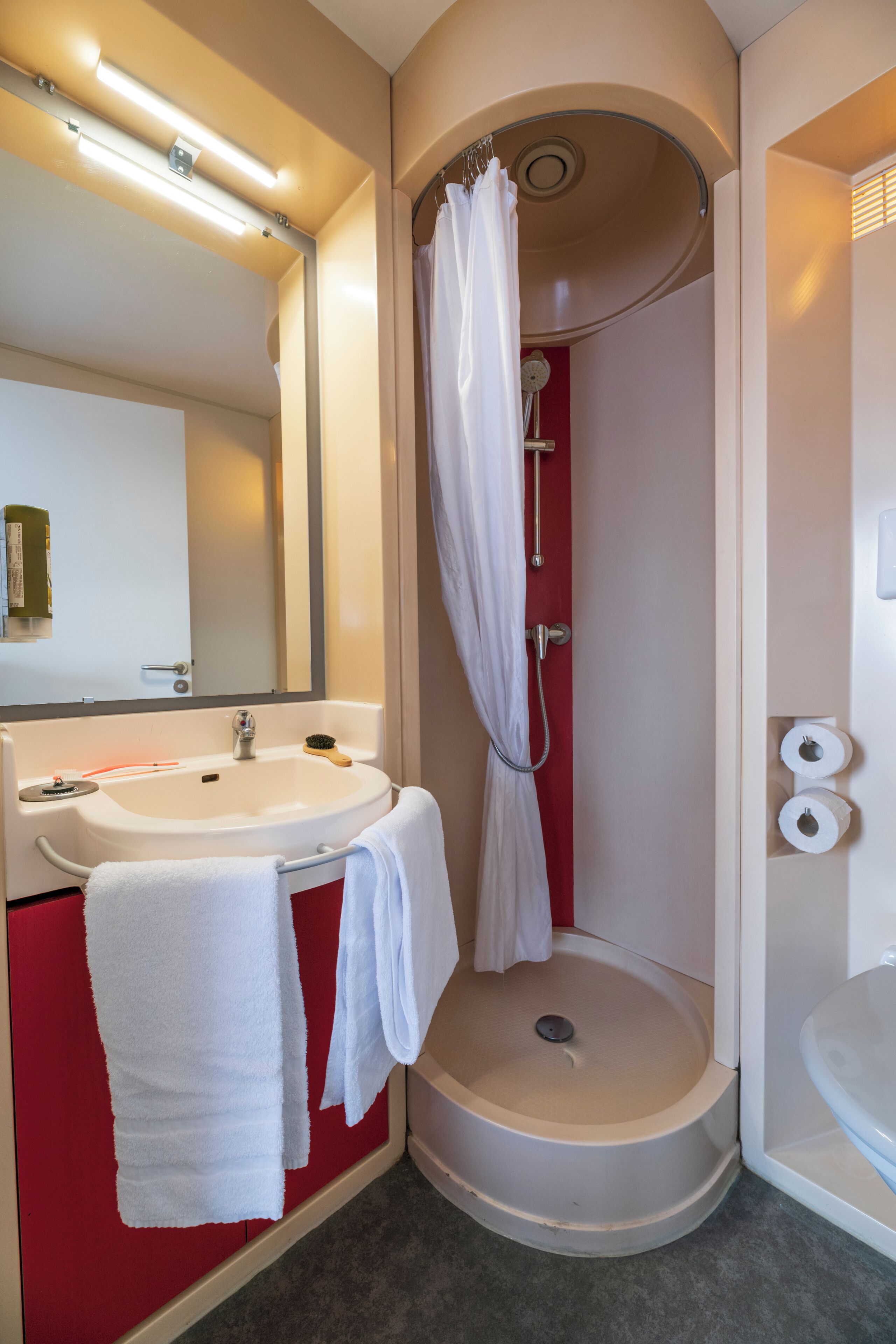Een badkamer met een wastafel, spiegel, douche en toilet.