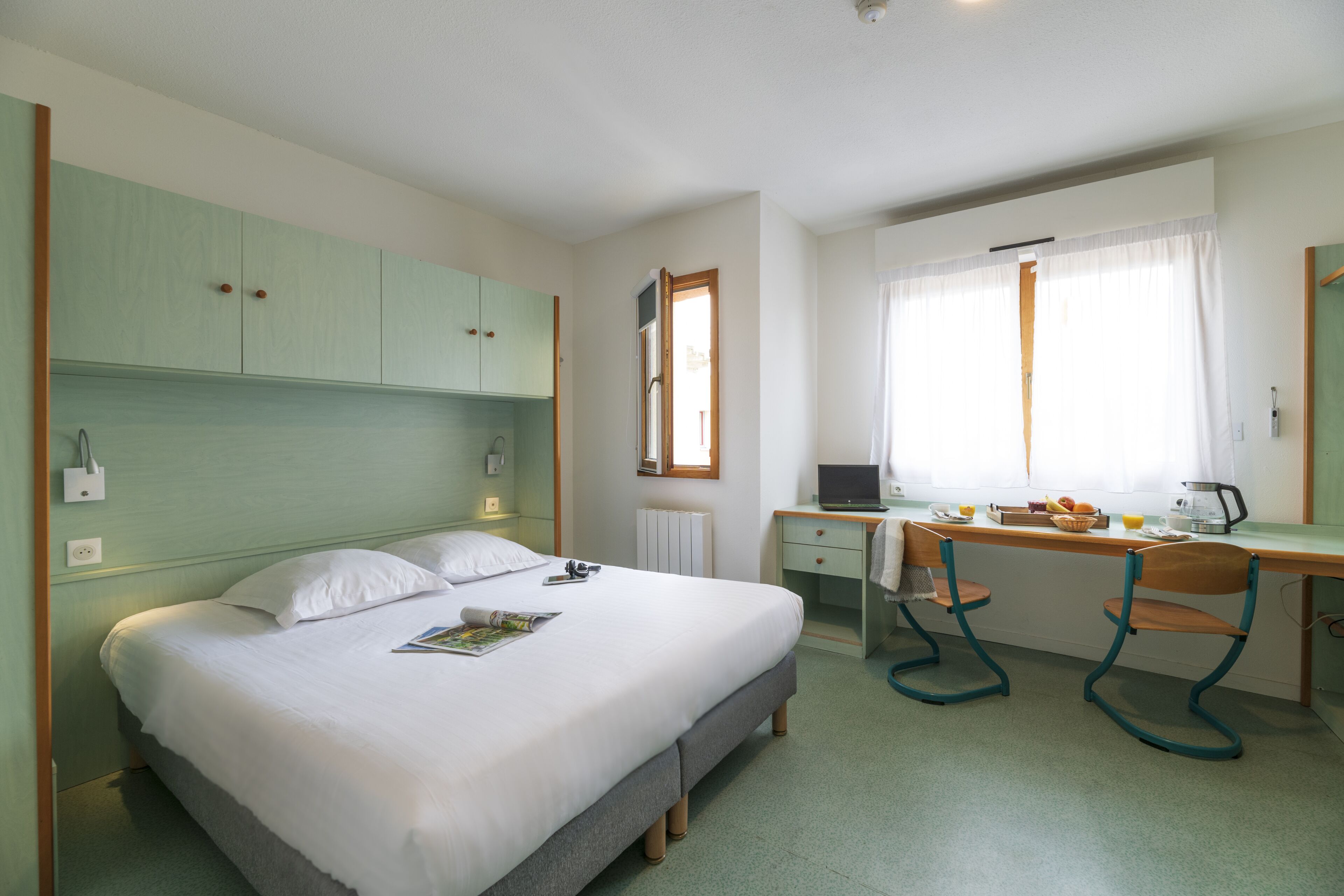 A bedroom with a bed, a desk, and a chair.