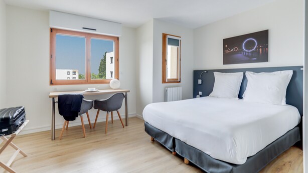 Een hotelkamer met een bed, bureau, stoelen en een raam met uitzicht.