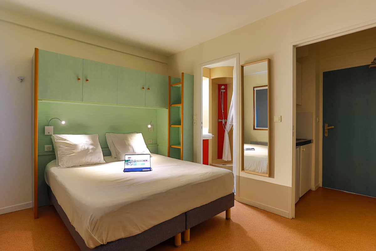 Un dormitorio con cama, armario, espejo y puerta.