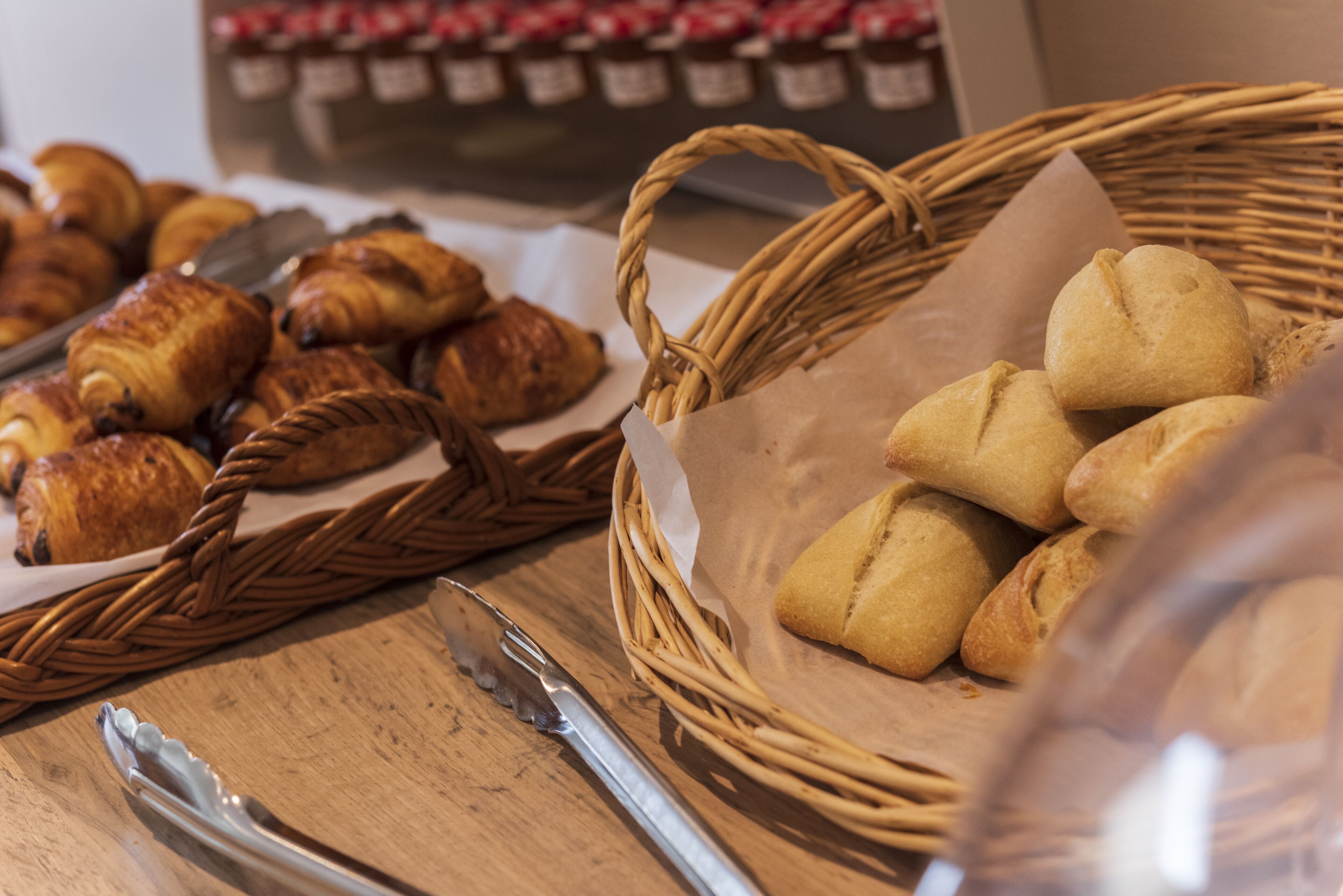 A wicker basket filled with bread and a knife on a wooden table.
