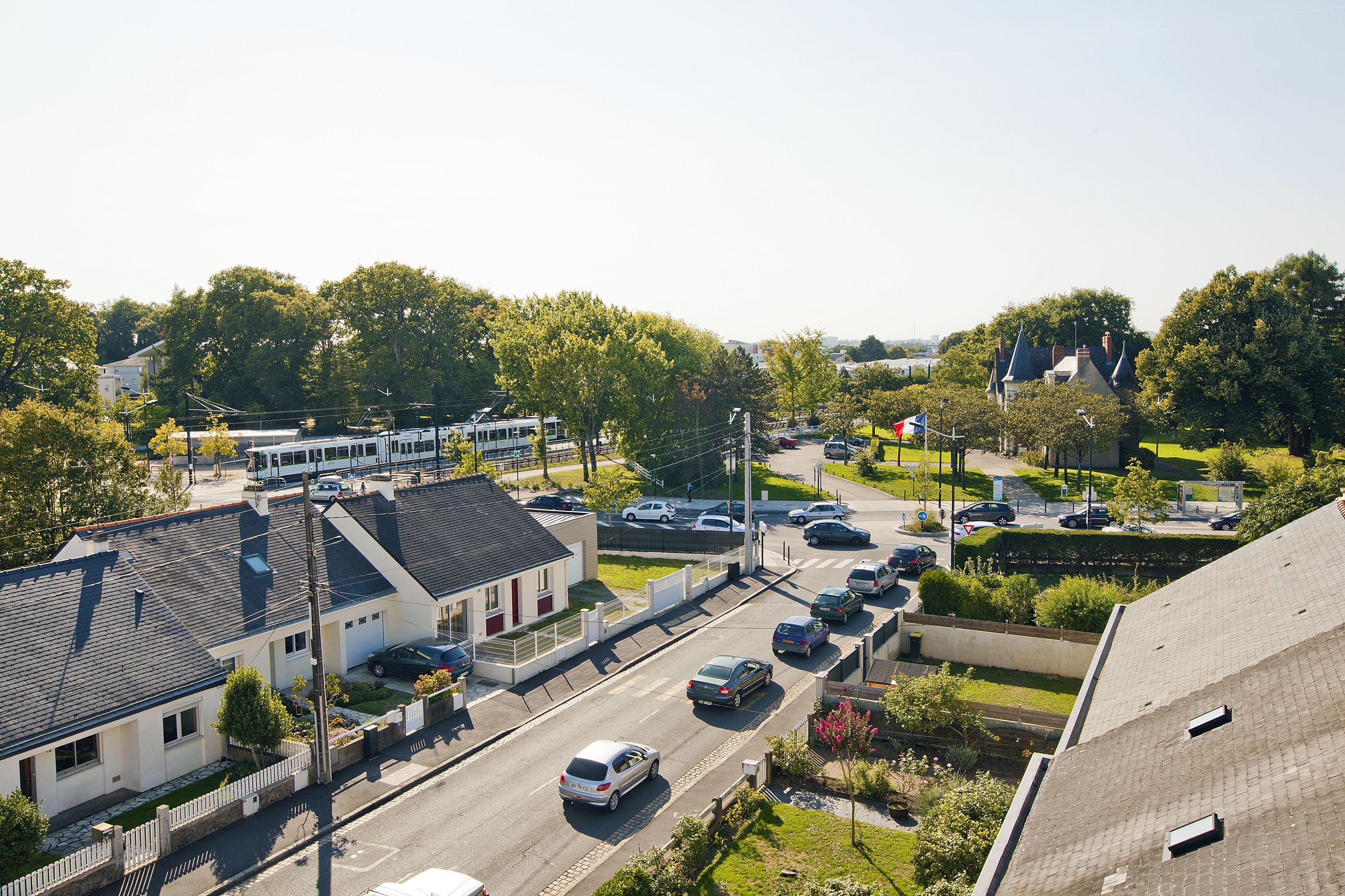 A residential street with houses, cars, and a tram.