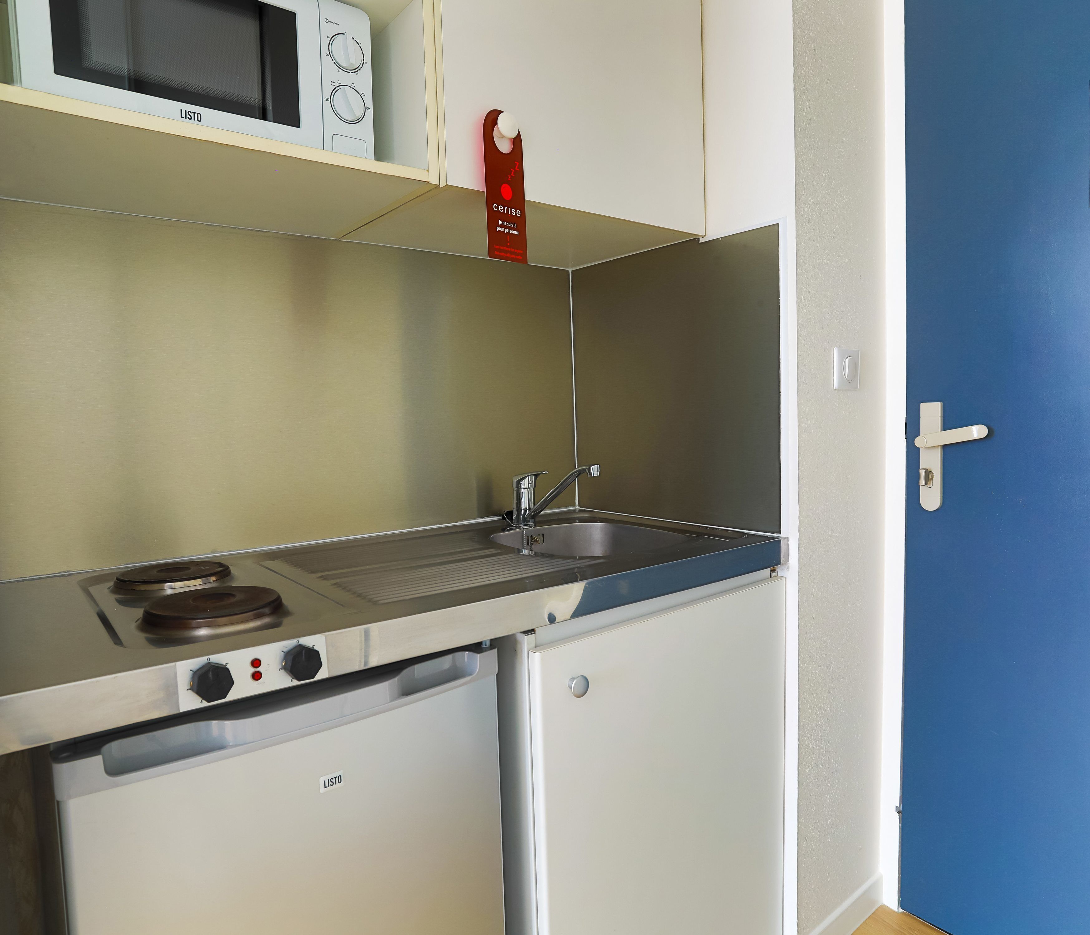 A compact kitchenette with a microwave, stove, and sink.