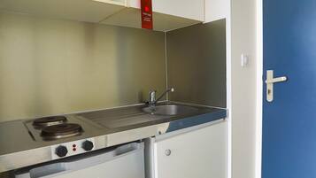 A compact kitchenette with a microwave, stove, and sink.