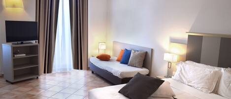 A hotel room with a bed, a TV, a nightstand, and a lamp.