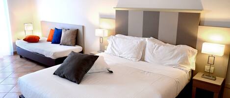 A hotel room with two beds, each with white linens and pillows, and bedside lamps.