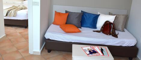 A bedroom with a bed, pillows, a magazine, and a handbag.