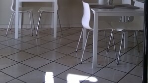 Un comedor moderno con una mesa y sillas blancas, un cuadro en la pared y un piso de baldosas.