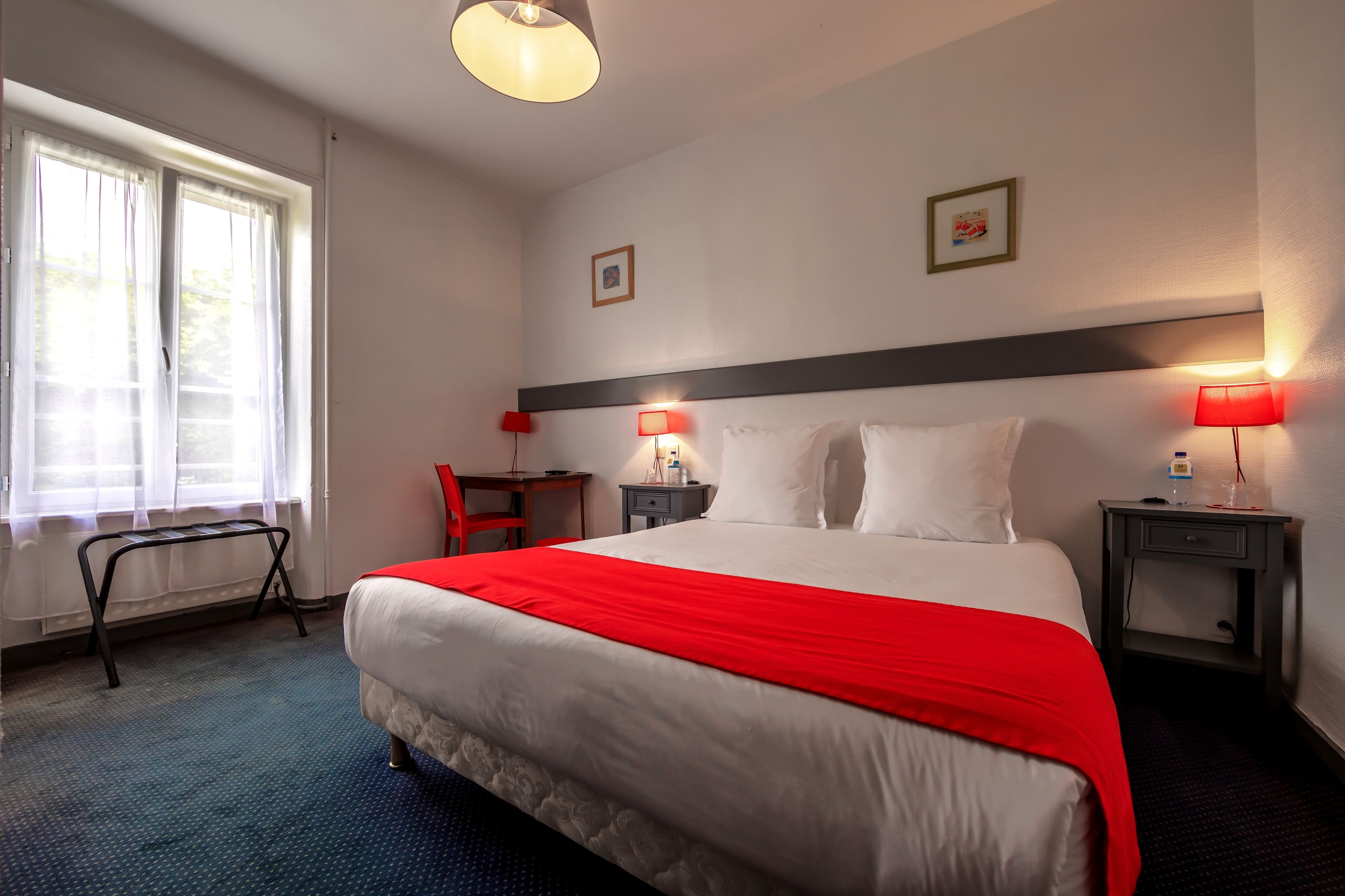 Une chambre d’hôtel avec un grand lit, deux tables de chevet avec des lampes, un petit bureau et une chaise.
