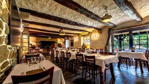 A restaurant with stone walls, wooden beams, and tables set for dining. - Logis Auberge de Kerveoc'h (Douarnenez)